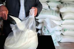 شکر سفید در حال ریخته شدن درون کیسه پلاستیکی شفاف