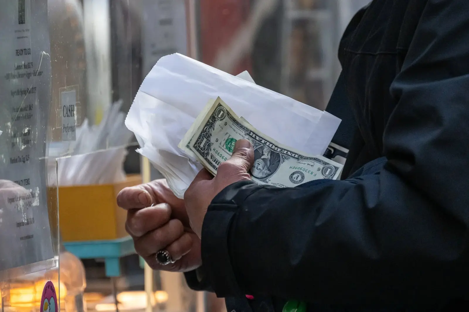اسکناس یک دلاری (US Dollar) در دست فردی در محیطی عمومی