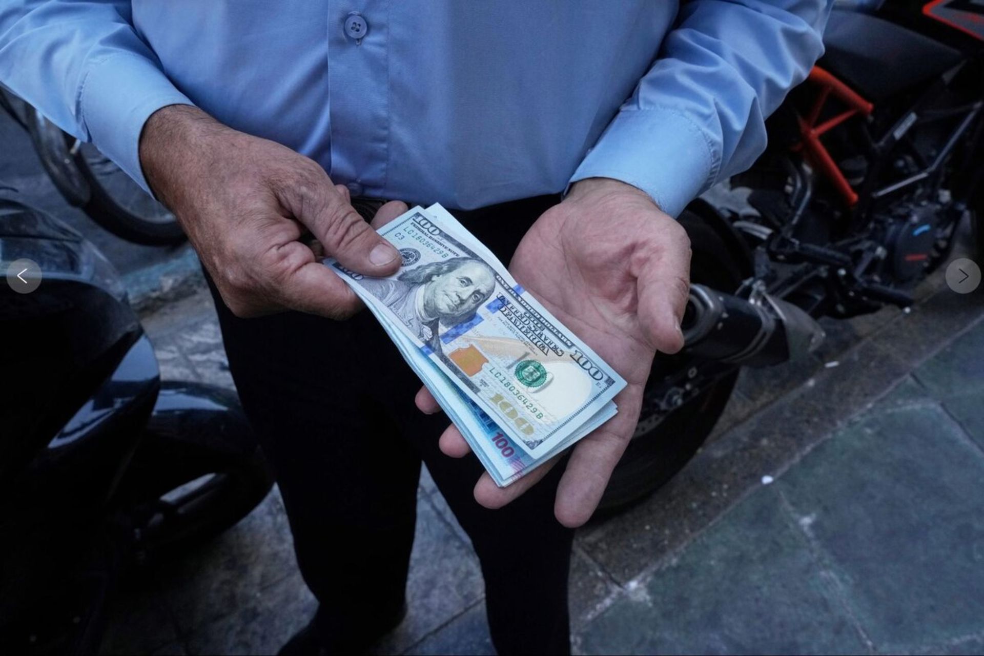 یک دسته اسکناس دلار در دست یک معامله گر در بازار غیر رسمی تهران