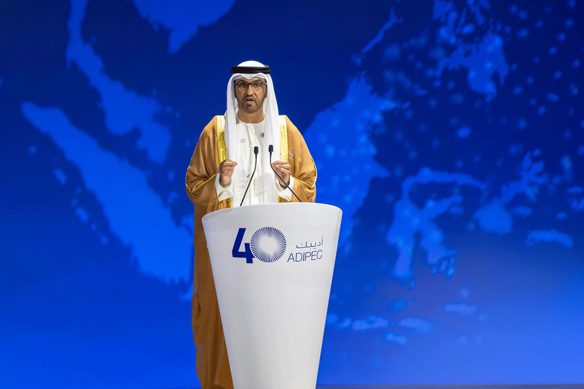 مردی با پوشش سنتی عربی در حال سخنرانی پشت تریبون ادی‌پک (ADIPEC)