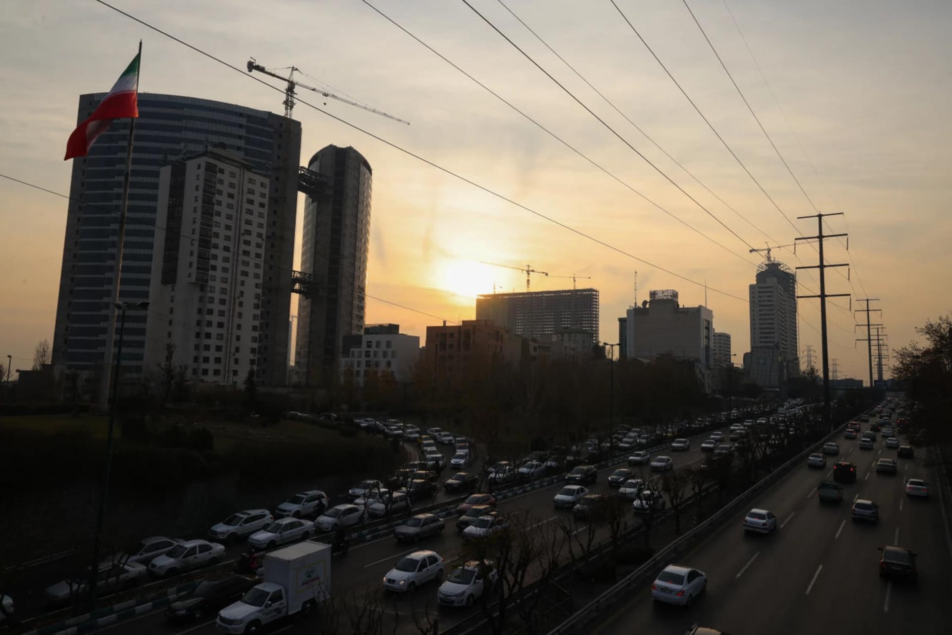 ترافیک خودروها در اتوبان تهران هنگام غروب خورشید در میان ساختمان‌ها