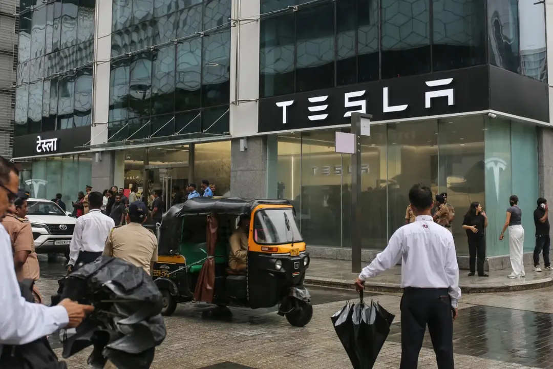 نمای ساختمان و لوگوی تسلا (Tesla) در خیابان با عبور ریکشا