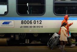 مسافران با چمدان در کنار واگن قطار شرکت راجا (Raja Rail Transportation Co)