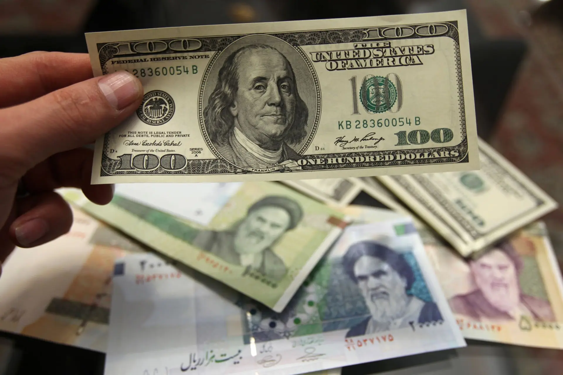 اسکناس صد دلاری آمریکا در کنار چند اسکناس ریال ایران
