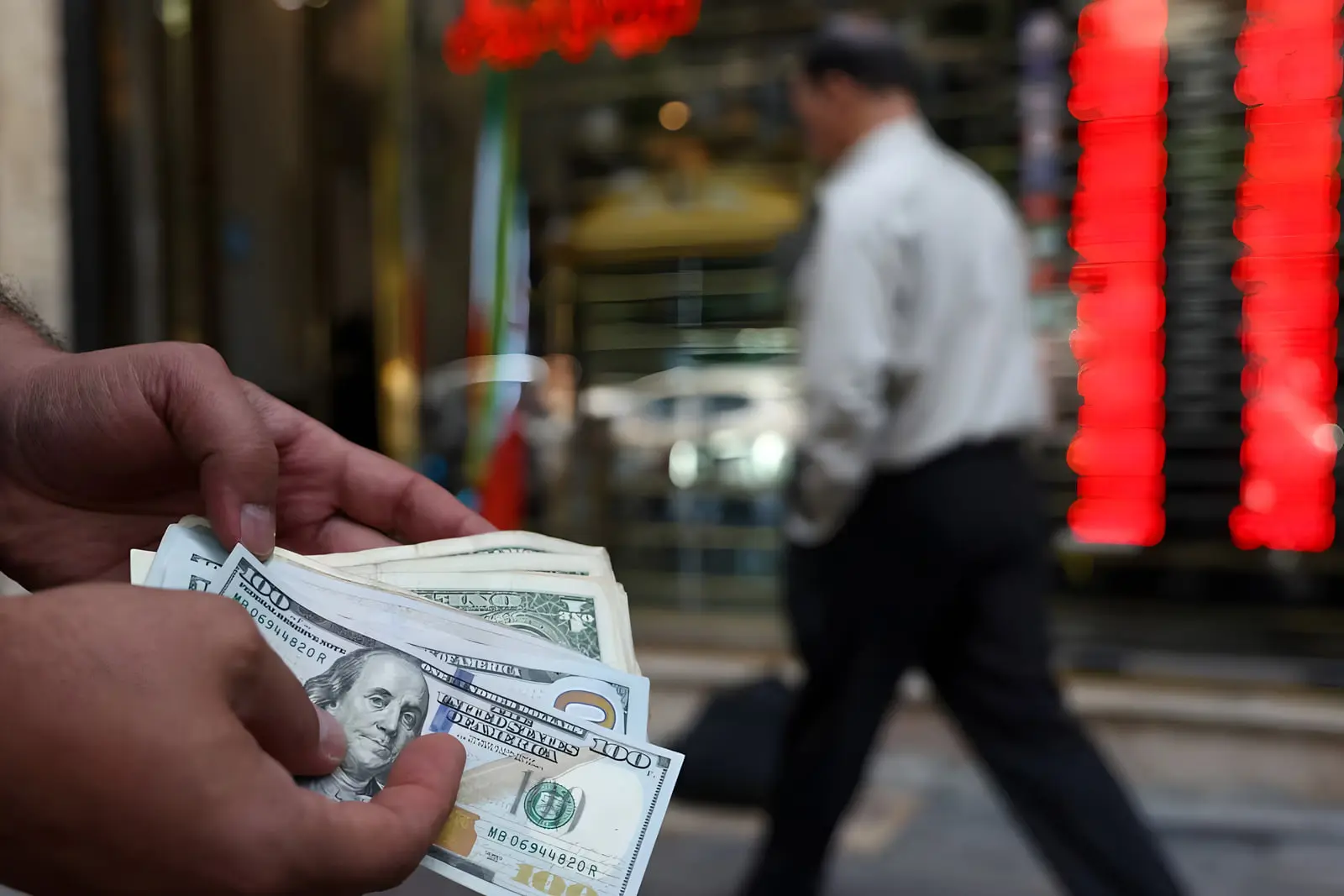 دست‌های فردی که اسکناس‌های ۱۰۰ دلاری (US Dollar) را در دست دارد