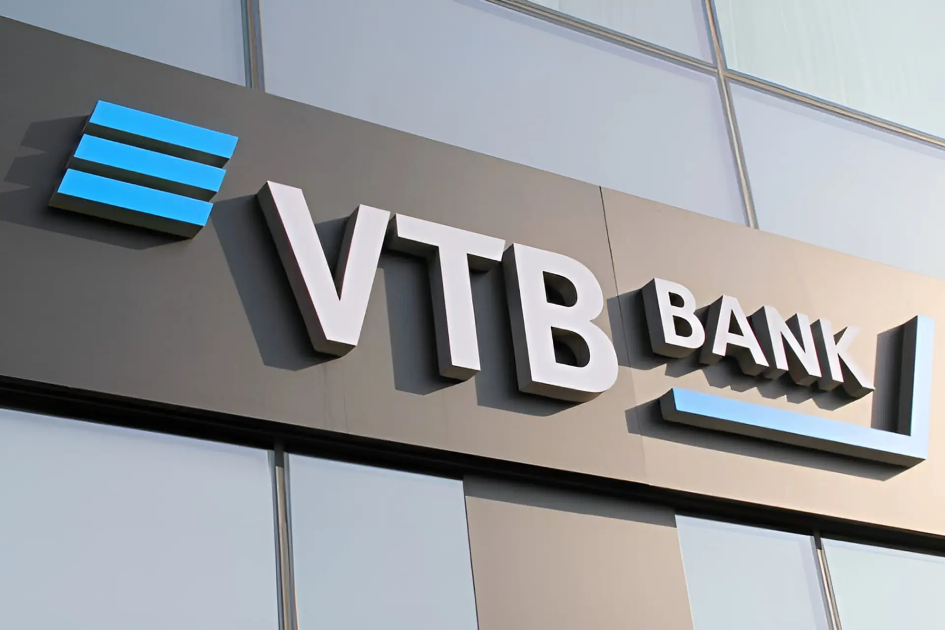نمای نزدیک از تابلوی لوگوی بانک وی‌تی‌بی (VTB Bank) روی نمای ساختمان