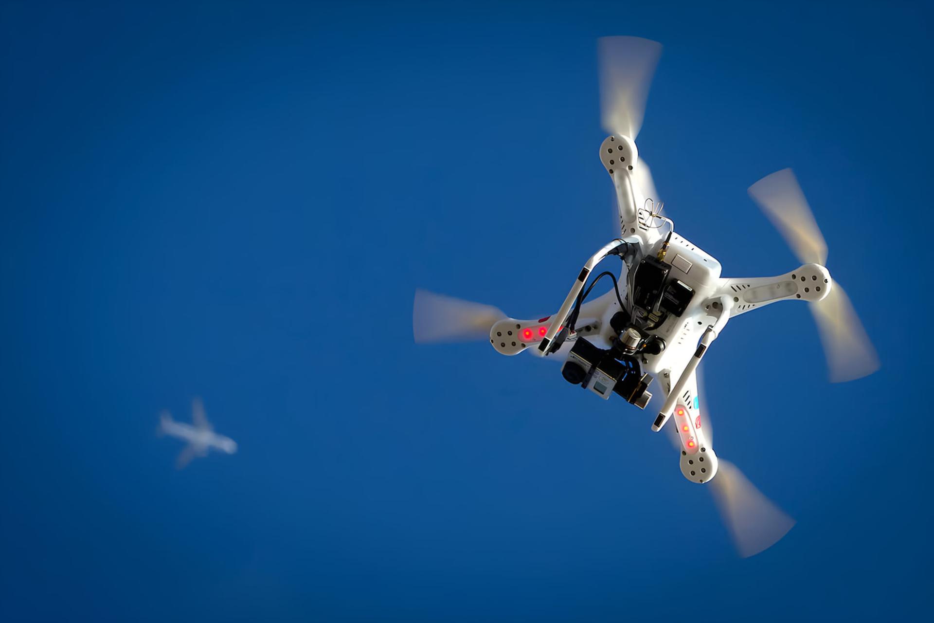 پهپاد کوادکوپتر (Quadcopter) سفید رنگ در حال پرواز در آسمان آبی